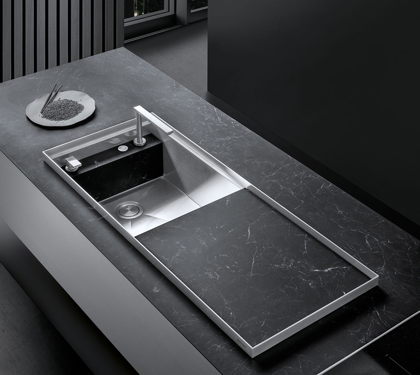 Vista aerea di un piano di cucina effetto marmorizzato con un lavello in acciaio inox dotato di rubinetto miscelatore e coperchio con chiusura a scorrimento