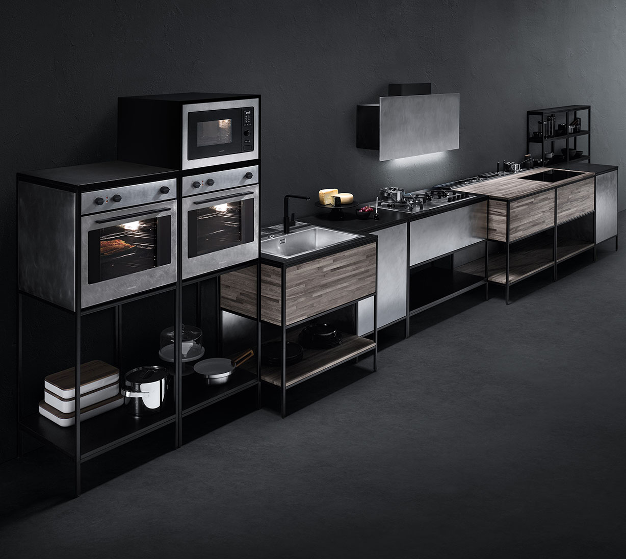 Visione di una cucina composta da vari elementi fra cui due forni, un forno microonde, un piano cottura sovrastato da cappa aspirante, due lavelli e varie superfici d'appoggio.