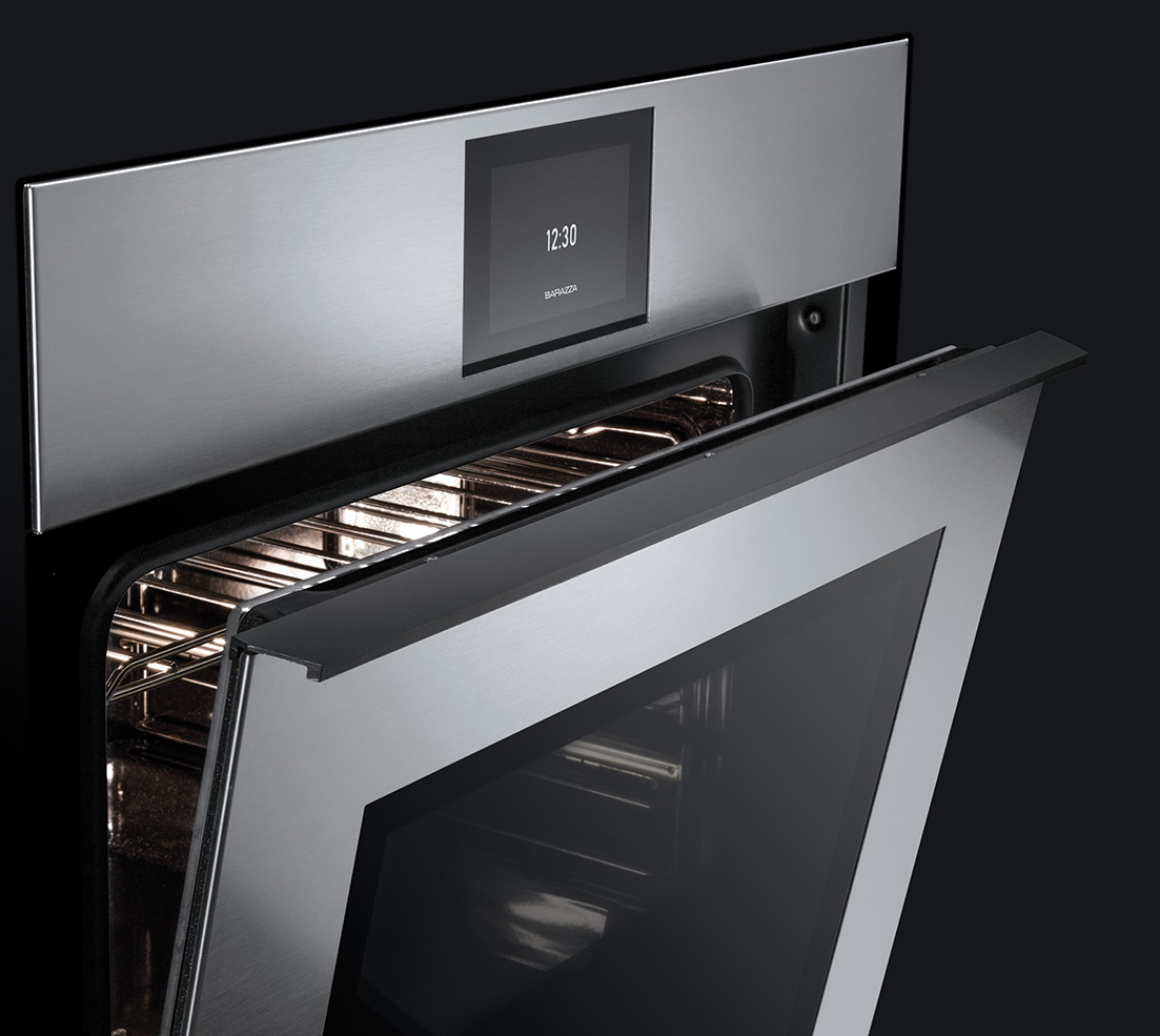 Dettaglio di un forno a incasso in acciaio inox con sportello leggermente aperto che lascia intravedere l'interno