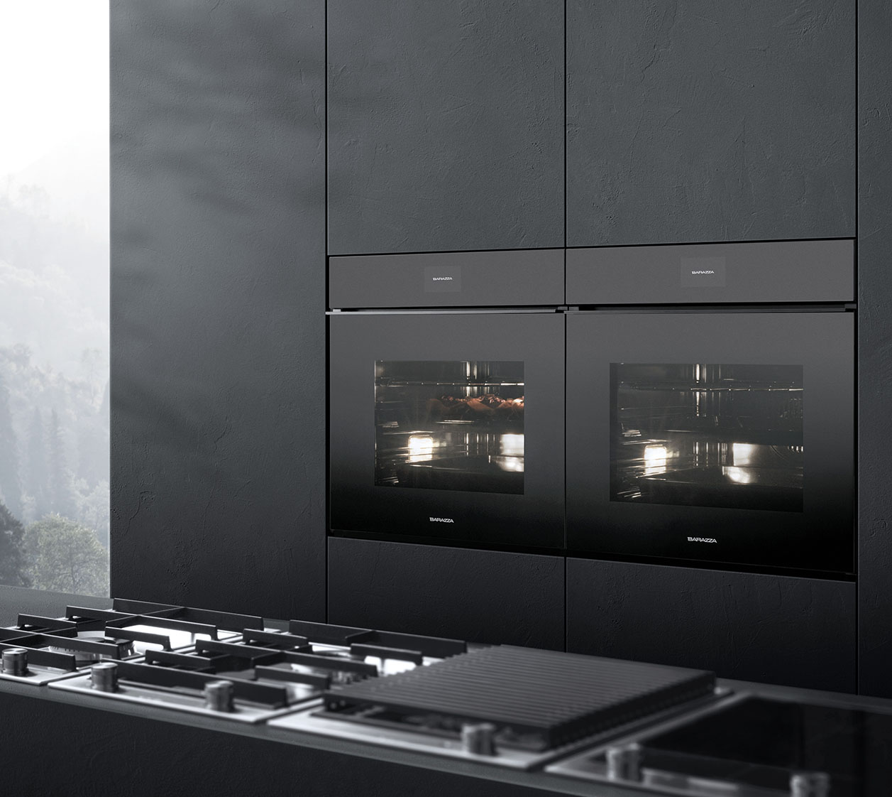 Vista di una cucina con due forni a incasso sullo sfondo e in primo piano, ma fuori fuoco, diverse tipologie di piani cottura