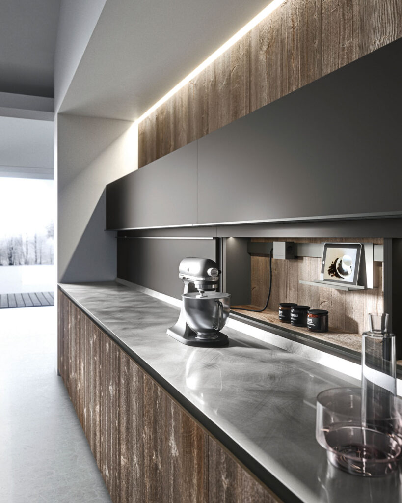 Dettaglio di una cucina che mostra un piano in acciaio montato su un mobile in legno sul quale poggia un accessorio di cottura e degli oggetti decorativi e, dietro il quale, figura una parete attrezzata con armadietti e accessori