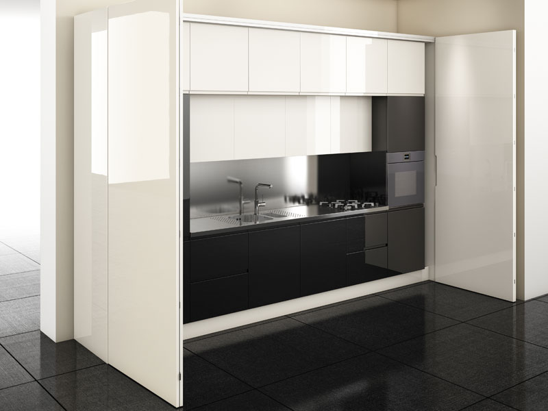Vista frontale di una cucina, bianca e nera, contenente un piano su cui si affiancano lavello, piano cottura a gas e un forno incassato nel mobile verticale di destra.