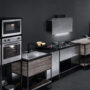 Visione di una cucina composta da vari elementi fra cui due forni, un forno microonde, un piano cottura sovrastato da cappa aspirante, due lavelli e varie superfici d'appoggio.