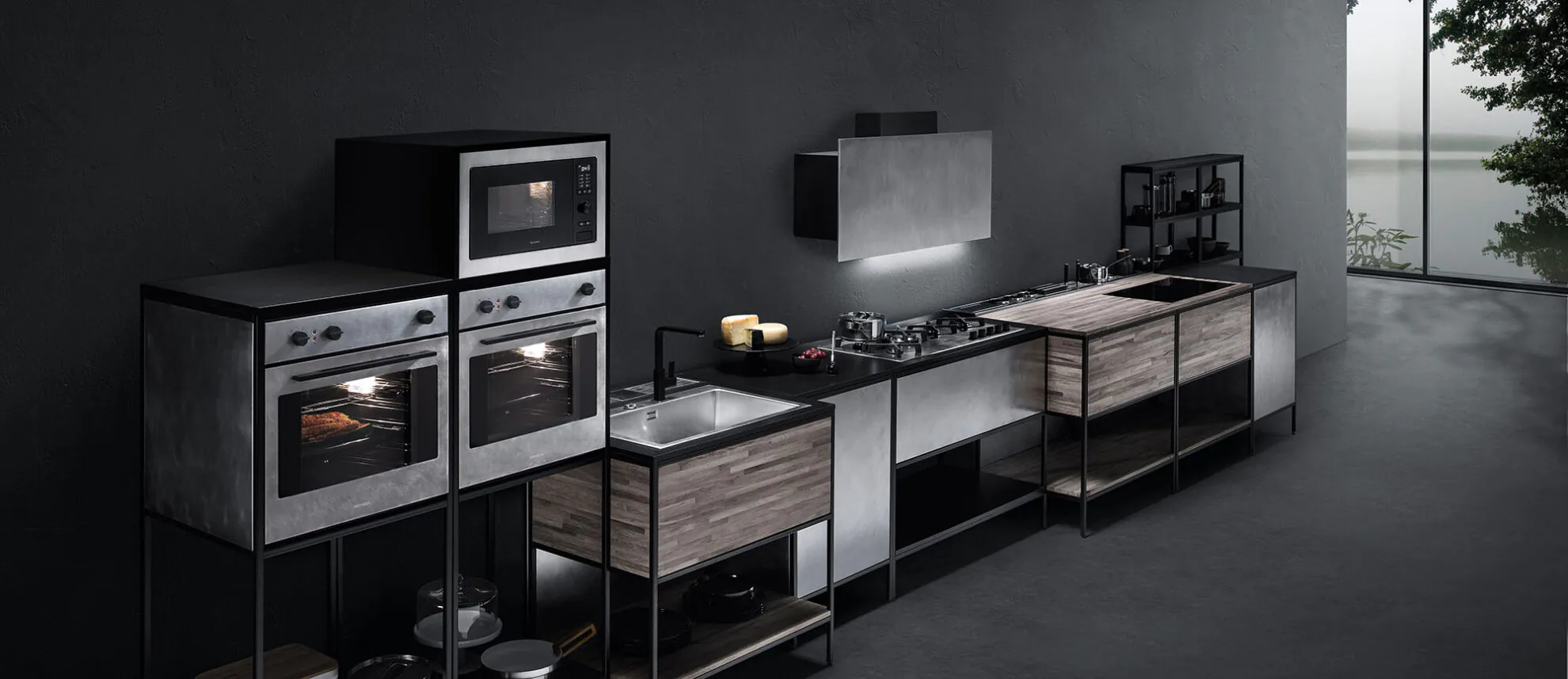 Visione di una cucina composta da vari elementi fra cui due forni, un forno microonde, un piano cottura sovrastato da cappa aspirante, due lavelli e varie superfici d'appoggio.