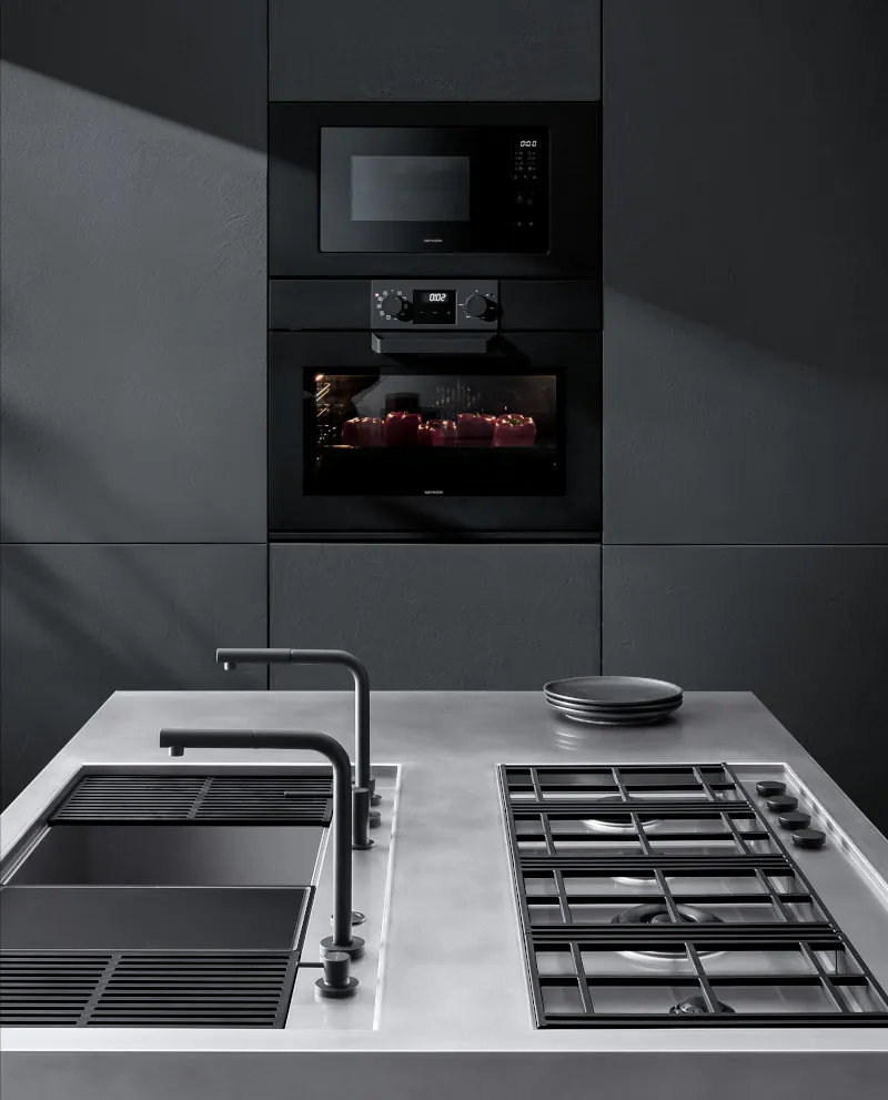 Cucina Barazza con lavelli a sinistra, piano cottura a destra e due forni integrati nel muro sullo sfondo tra cui uno accesso.